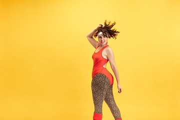 Image showing Young caucasian plus size female model\'s training on yellow background