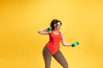 Image showing Young caucasian plus size female model\'s training on yellow background