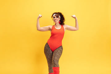 Image showing Young caucasian plus size female model\'s training on yellow background