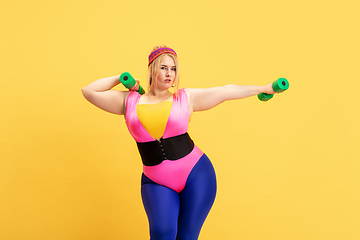 Image showing Young caucasian plus size female model\'s training on yellow background