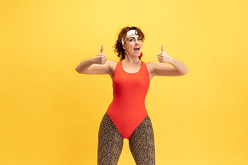 Image showing Young caucasian plus size female model\'s training on yellow background