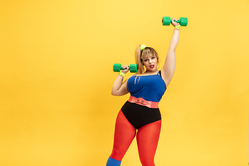 Image showing Young caucasian plus size female model\'s training on yellow background