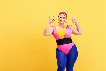 Image showing Young caucasian plus size female model\'s training on yellow background