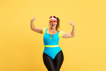 Image showing Young caucasian plus size female model\'s training on yellow background