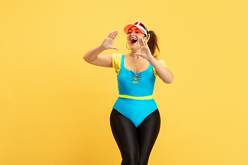 Image showing Young caucasian plus size female model\'s training on yellow background