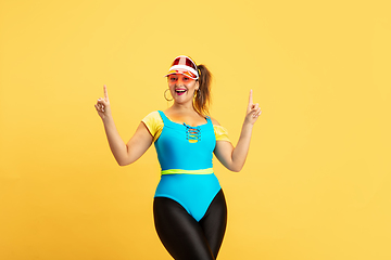 Image showing Young caucasian plus size female model\'s training on yellow background