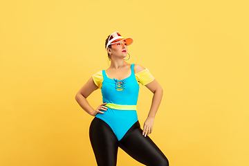 Image showing Young caucasian plus size female model\'s training on yellow background