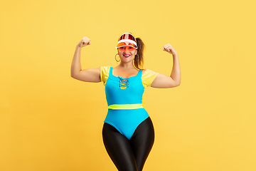 Image showing Young caucasian plus size female model\'s training on yellow background