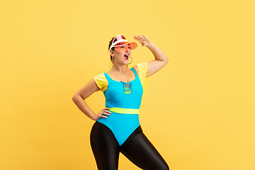 Image showing Young caucasian plus size female model\'s training on yellow background