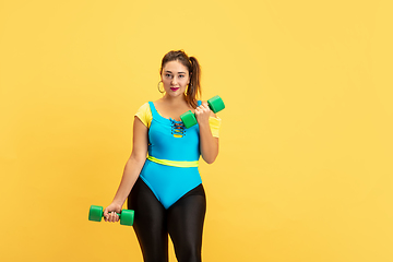 Image showing Young caucasian plus size female model\'s training on yellow background