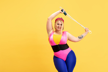 Image showing Young caucasian plus size female model\'s training on yellow background