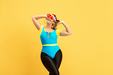Image showing Young caucasian plus size female model\'s training on yellow background