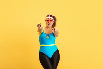 Image showing Young caucasian plus size female model\'s training on yellow background