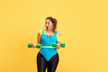 Image showing Young caucasian plus size female model\'s training on yellow background