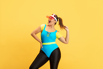 Image showing Young caucasian plus size female model\'s training on yellow background