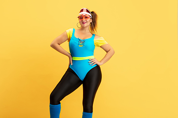 Image showing Young caucasian plus size female model\'s training on yellow background