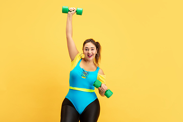 Image showing Young caucasian plus size female model\'s training on yellow background