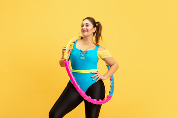 Image showing Young caucasian plus size female model\'s training on yellow background