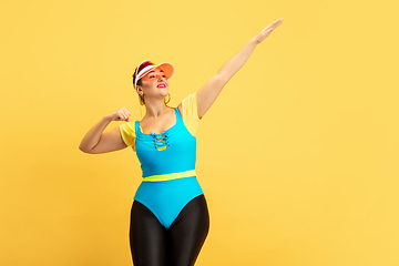 Image showing Young caucasian plus size female model\'s training on yellow background