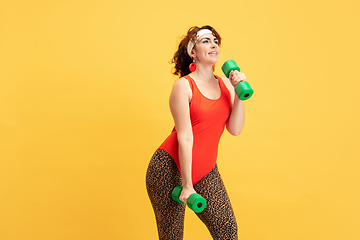 Image showing Young caucasian plus size female model\'s training on yellow background