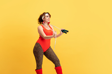 Image showing Young caucasian plus size female model\'s training on yellow background