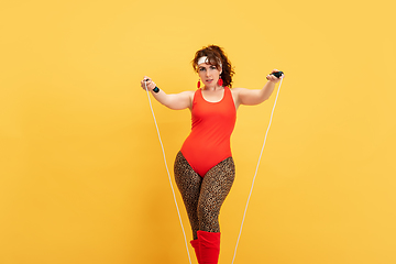 Image showing Young caucasian plus size female model\'s training on yellow background