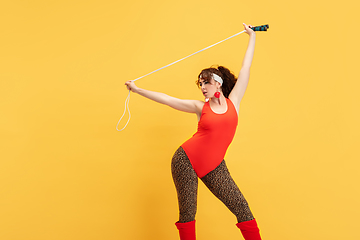 Image showing Young caucasian plus size female model\'s training on yellow background