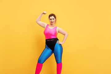 Image showing Young caucasian plus size female model\'s training on yellow background