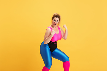 Image showing Young caucasian plus size female model\'s training on yellow background