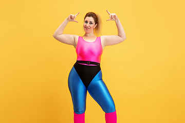 Image showing Young caucasian plus size female model\'s training on yellow background