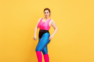 Image showing Young caucasian plus size female model\'s training on yellow background