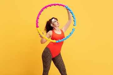 Image showing Young caucasian plus size female model\'s training on yellow background