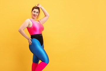 Image showing Young caucasian plus size female model\'s training on yellow background