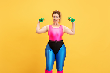 Image showing Young caucasian plus size female model\'s training on yellow background