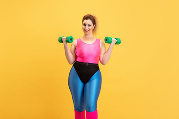 Image showing Young caucasian plus size female model\'s training on yellow background