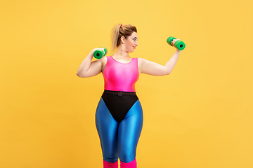 Image showing Young caucasian plus size female model\'s training on yellow background