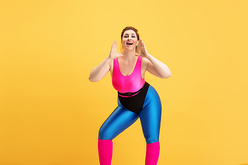 Image showing Young caucasian plus size female model\'s training on yellow background