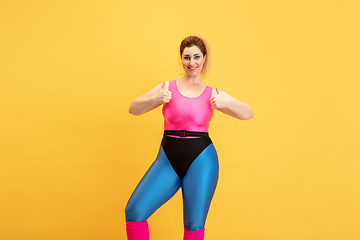 Image showing Young caucasian plus size female model\'s training on yellow background