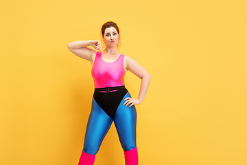 Image showing Young caucasian plus size female model\'s training on yellow background