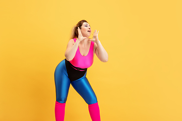 Image showing Young caucasian plus size female model\'s training on yellow background