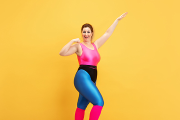 Image showing Young caucasian plus size female model\'s training on yellow background