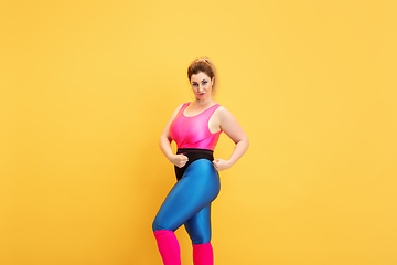 Image showing Young caucasian plus size female model\'s training on yellow background