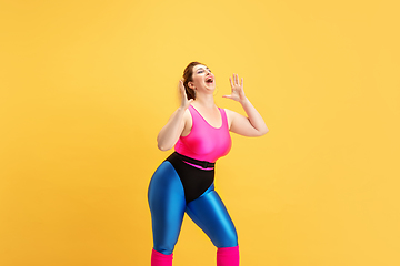 Image showing Young caucasian plus size female model\'s training on yellow background