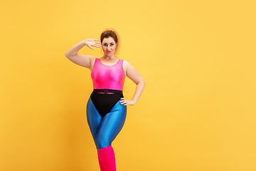 Image showing Young caucasian plus size female model\'s training on yellow background