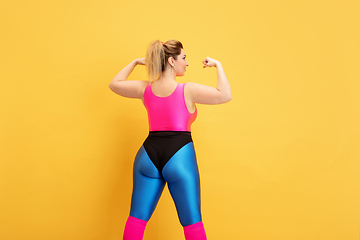 Image showing Young caucasian plus size female model\'s training on yellow background