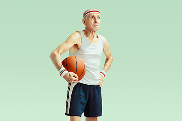 Image showing Senior man playing basketball in sportwear isolated on green background