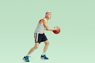 Image showing Senior man playing basketball in sportwear isolated on green background