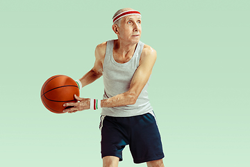 Image showing Senior man playing basketball in sportwear isolated on green background