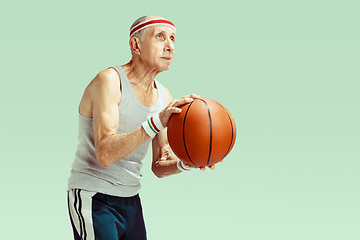 Image showing Senior man playing basketball in sportwear isolated on green background