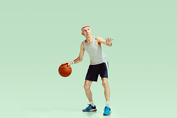 Image showing Senior man playing basketball in sportwear isolated on green background